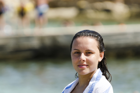Portrait of happy girl smiling on the beach wrapped in a towelの写真素材