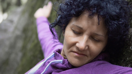 Cinematic view of thoughtfull woman in depression touching the stone moss in nature and exchanging...