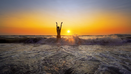 Sexy woman with perfect body running and jumping in sea water on sand beach at sunset, cinematic SLOW MOTIONの写真素材
