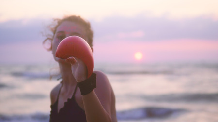 Karate sport girls exercise, training karate on ocean beach against sunset, focus to glovesの写真素材