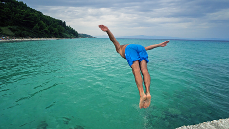 Attractive man jumping into waterの写真素材