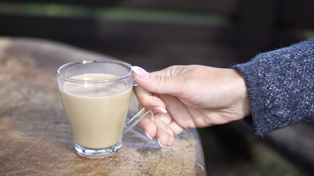Closeup shot of adult woman relaxing at outdoors drinking a cup of coffeeの写真素材