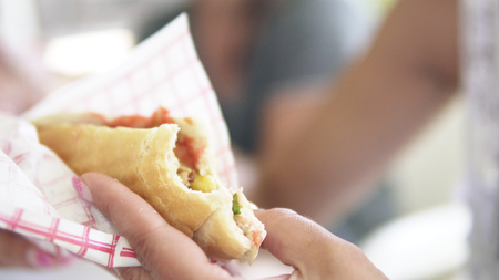 Young woman is eating doner kebab at lunch bites a delicious juicy shawarma. Fast food conceptの写真素材