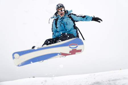 Snowboarder jumping through air with gray skyの写真素材
