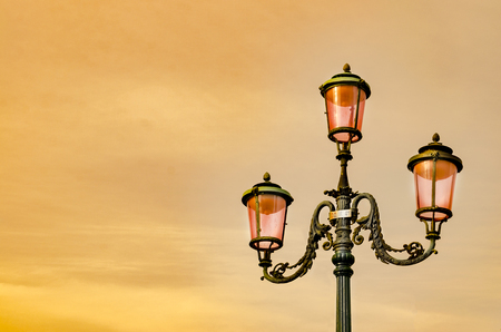 lantern street lights of San Marco's square against sunset orange sky, in Venice, Italyの写真素材