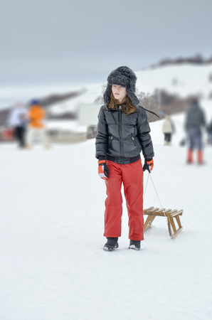 Cute little girl pulling old sled wooded vintage schlitten holz on winter snowの写真素材