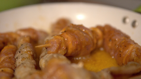Frying a pork skewers in pan on gas stove, made of white meat and baconの写真素材