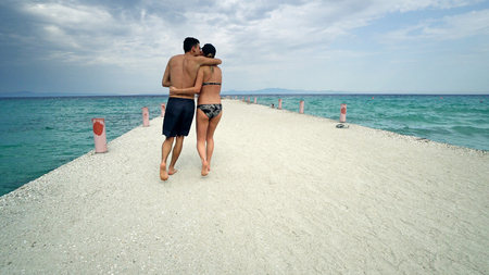 Romantic couple in bikini walking on beach pierの写真素材