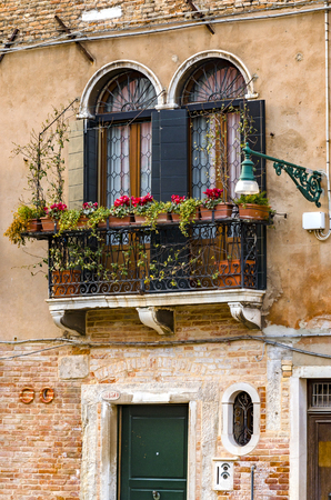 old balconies in a Venice colorful building with red flowers, verticalの写真素材