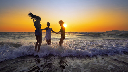 Young fun party of people dancing and spraying at the beach sunset.Concept of friendly family.の写真素材