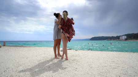 Funny female friends on vacation taking selfies on the beach with a smart phoneの写真素材