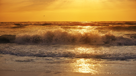 Storm waves splash sea at sunsetの写真素材