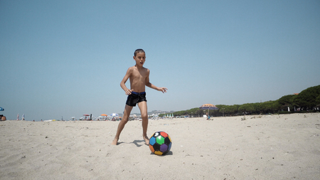 Boy playing football on the beach, SLOW MOTIONの写真素材