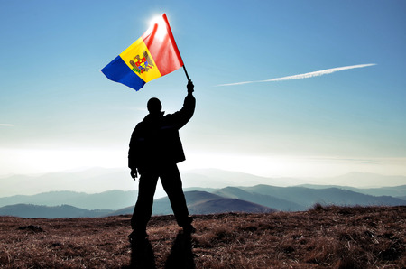 Successful silhouette man winner waving Moldova flag on top of the mountain peakの写真素材
