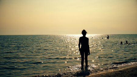 Silhouette fashion model out of sea water at sunset, sunriseの写真素材