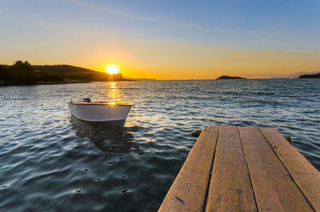 Boat on the pier at sunset on a background of sea and mountainsの写真素材