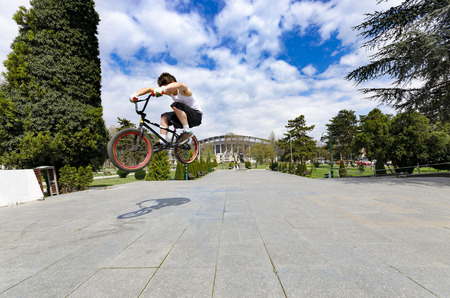 Skopje, Macedonia - circa Apr, 2013: Below view of skillful cyclist jumping high up against skyのeditorial素材