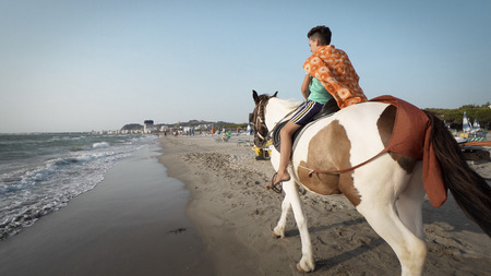 Handsome young boy riding a horse on a tropical beachのeditorial素材