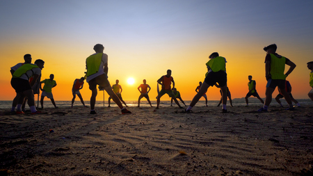 Football team training of young boys on the sunset beach, cinematic steadicam shotのeditorial素材