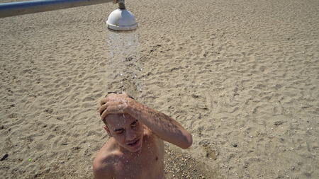 Close up of a young man showering on beachの写真素材