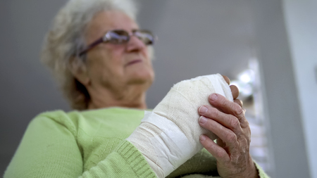 Old woman massage her injured broken hand sitting, cinematic dof
