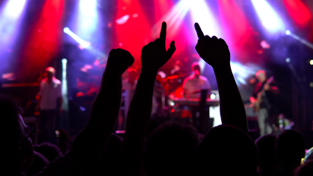 Silhouettes of concert crowd in front of bright stage lights. Public concert, no ticketing eventの写真素材