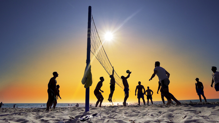 Silhouettes of young men playing volleyball on Varkala beach at sunset, Durres, Albania, SLOW MOTIONの写真素材