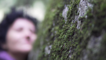 Cinematic view of thoughtfull woman in depression touching the stone moss in nature and exchanging...