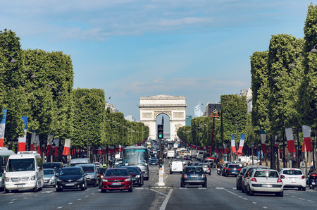 Traffic down the Champs Elysees and the Arch de Triomphe with French flags on trees waving celebrating national holliday in Paris, Franceのeditorial素材