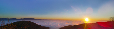 Panorama of high mountain sunset with valley covered with mist, fogの写真素材