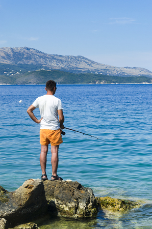 Fishermen standing on the rocks at daytime, verticalの写真素材