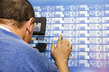 Printing Plant - Print Operator Makes Calibration Controll of Computer to plate pattern on plates looking with magnifying glass. CTP is an imaging technology used in printing processesの写真素材