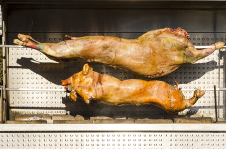 Roasting whole piglet pig and lamb grilled at street food marketの写真素材