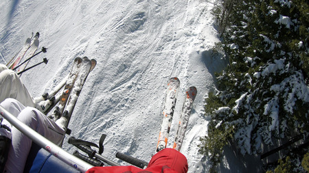 Ski lift dragging through a pine forest area at sunrise to the mountain ski slopes winter resortの写真素材