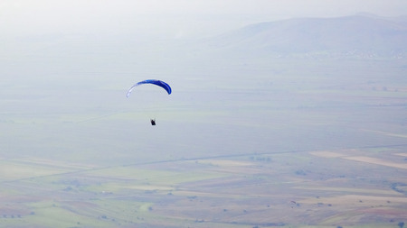 Silhouette of paraglide flying high over valleyの写真素材