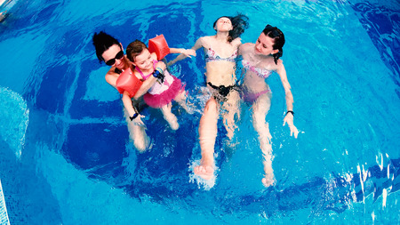 Aerial view of family relaxing in luxury outdoors pool, slow motionの写真素材