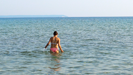 Female teen enter sea water, summer beach refreshmentの写真素材
