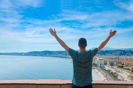 Tourist enjoying view over panoramic city of Nice in France with hands wide open over horizon, freedom conceptの写真素材
