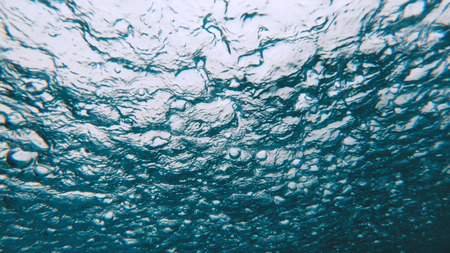 Underwater view of heavy raining into the water surface