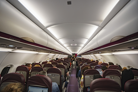 Paris, France - 05 May, 2017: Interior of large passengers airplane illuminated at night with people on seats and family with baby walking the aisle.のeditorial素材