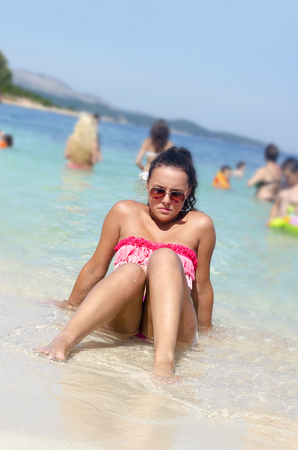 Summer girl sea. Girl sitting on beach of seaのeditorial素材