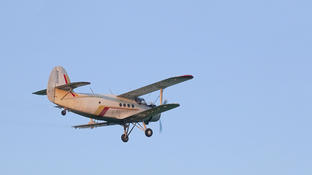 A crop duster applies chemicals to a field of vegetationの写真素材