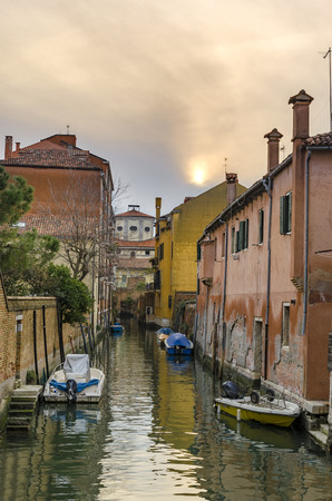 Boats and Gondola in picturesque Venice Canal at sunset, view of typical architecture colorful housesの写真素材