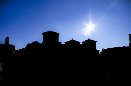 Silhouette of orthodox monastery backlit by sun on blue skyの写真素材