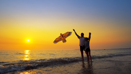A little boy and father play launching a kite at sunset, summer vacation conceptの写真素材