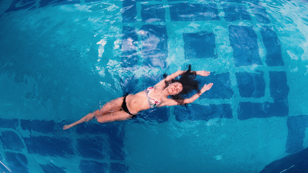 Directly above happy female swimming in a pool. Aerial viewの写真素材