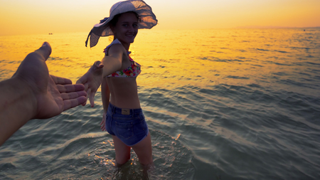 Couple romance, happy smiling teen with hat holding hands leading boyfriends towards beach sunset. travel conceptの写真素材