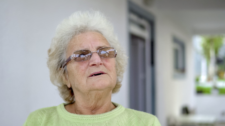 Portrait of elderly white sad woman sitting and thinking outdoorsの写真素材