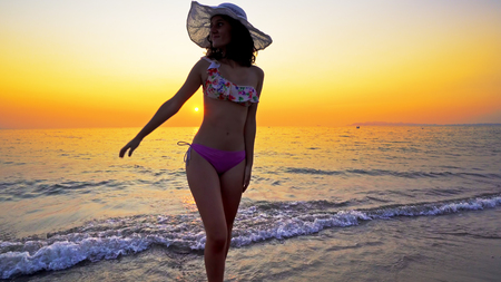 Sexy teen in bikini and hat go out of sea water at sunset, Summer vacation conceptの写真素材