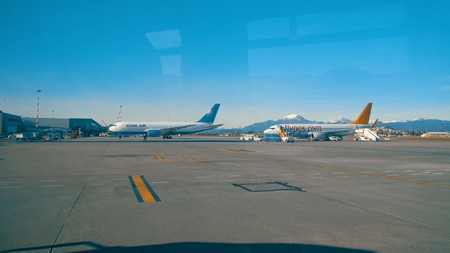 Treviso, Italy - circa Jan, 2018: Passenger POV from transportation bus at airport runaway to parked planes and cargo transportation vehicles, visible wind reflectionsのeditorial素材